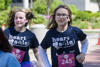 two Heart and Sole participants smile in maroon Heart and Sole shirts at a local practice